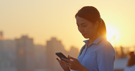 Woman use of smart phone under sunset in Hong Kong