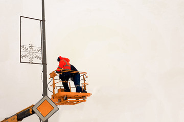 workers on the manipulator hang Christmas illumination
