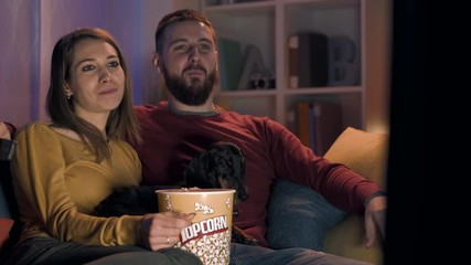 Happy couple watching TV together at home - Powered by Adobe