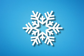 Snowflake shape made from cut paper on blue background