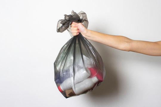 Female hand holds a trash bag with garbage on a light background. Separate trash concept, stop plastic