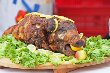 Roast pig. Roasted piglet with vegetables on platter