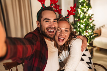 Photo of young pleased couple taking selfie photo and hugging