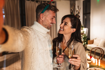 Photo of beautiful cheerful couple drinking champagne and taking selfie