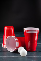 Wooden table with red cups and ball for beer pong