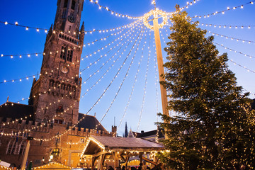Fototapeta premium Tradycyjny jarmark bożonarodzeniowy w Europie, Brugia, Belgia. Główny plac miejski z ozdobnym drzewem i światłami. Koncepcja świątecznych targów