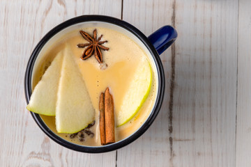 Mulled apple cider or punch on white wooden background, tea drink in blue metal mug, cinnamon and dried flowers of star anise, top view, copy space, Christmas cocktail for New Year