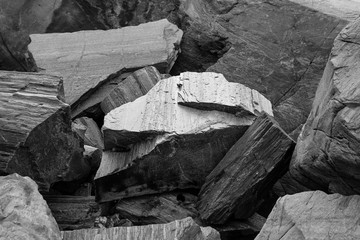 Rock structure close up. Pile of big gray stones on norwegian beach. Texture on the rock surface. Black and white abstract composition.  Stone glowing with light. Monochromatic. 