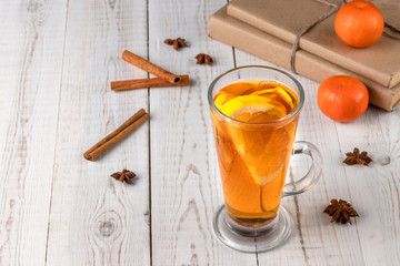 Mulled lemon cider or punch with books, tangerines and cinnamon, white wooden background, tea drink...