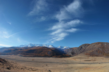 Fototapeta premium Mountain landscape. Spacious valley, snowy ridge and blue sky with white clouds.