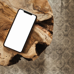 Blank screen smartphone with empty copy space mockup on solid wooden stool and carpet. Flat lay,...