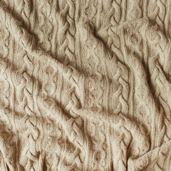 Beige knitted plaid blanket with ornament. Cozy decor textile concept.