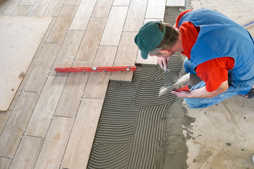 the worker puts ceramic tiles on the construction site