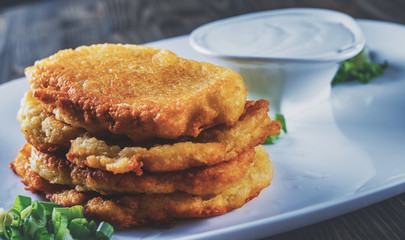 potato pancakes with sour cream in a plate on wooden table