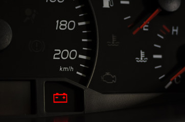 Close up shot of a car's dashboard with the battery icon lit.
