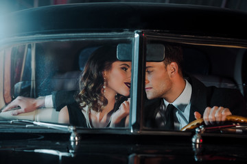 selective focus of handsome man and happy woman sitting in retro car
