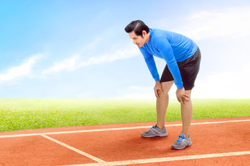 Obraz premium Asian runner man take a break after running on the running track