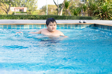 Asian boy is playing in a pool in Thailand.An obese boy swimming in the pool
