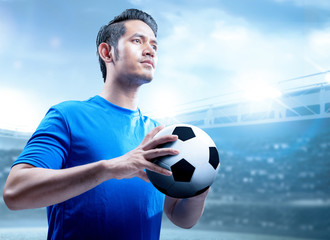 Asian football player man holding the ball on the football field