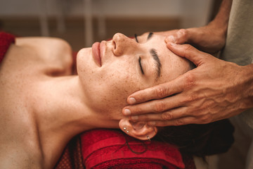 Fototapeta na wymiar Alternative Medicine. Therapist healing lying woman smiling peaceful close-up doing head ayurvedic massage pressing on forehead