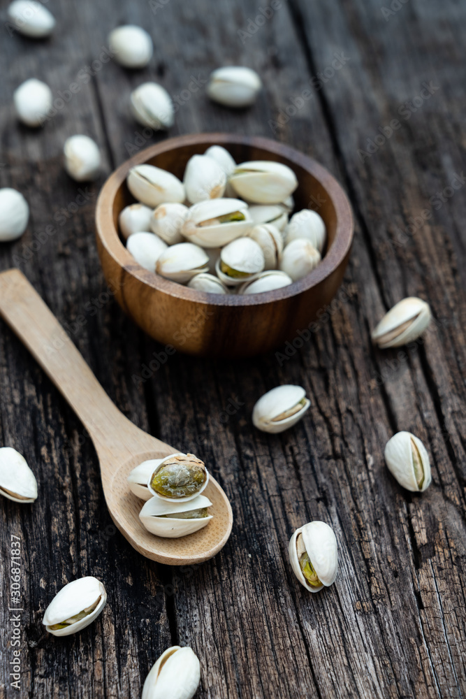 Wall mural Pistachio nut in wooden bowl on rusty wood table background - Wall murals