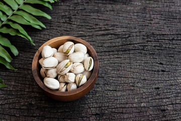 Pistachio nut in wooden bowl on rusty wood table background