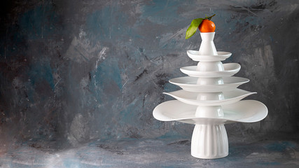 White dishes Pyramid of Christmas tree shape with mandarin with leaf on top, bunch below on dark Creative concept, dishware, veg, agriculture, vegetable, kitchen, restaurant, wallpaper, Xmas, New Year
