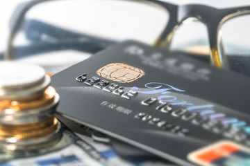 Stacked COINS and bank CARDS and credit CARDS are placed on the spread of dollars