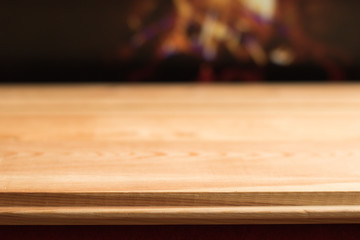 Close-up: Simple Wooden Table with Empty Space against Blurred Bright Burning Fire in Fireplace – Background, Banner, Copy Space. 