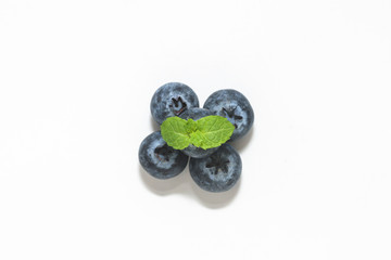 Blueberries and a mint leaf on a white background