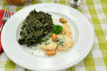 fillet of fish with cream and spinach on a plate