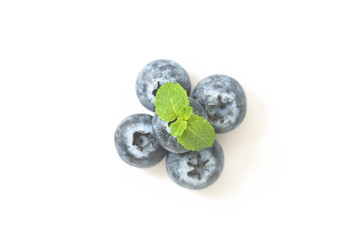 Blueberries and a mint leaf on a white background