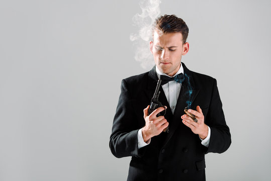 handsome gangster holding gun and cigar isolated on grey