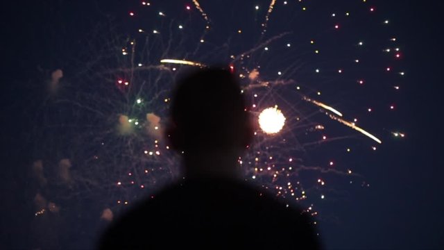 Blurred closeup silhouette of a man enjoying fireworks at night