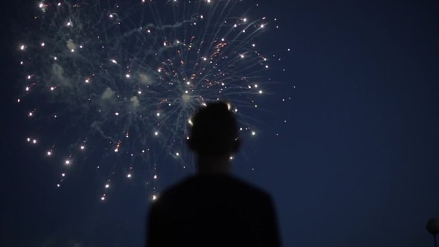 Blurred closeup silhouette of a man enjoying fireworks at night