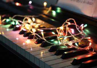 Piano keyboard with glowing colorful string light on it.