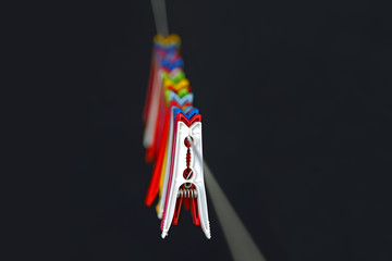 Colorful pegs lined up on rope on a black backdrop.
