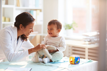 Female doctor playing with her little patient while examining him at hospital