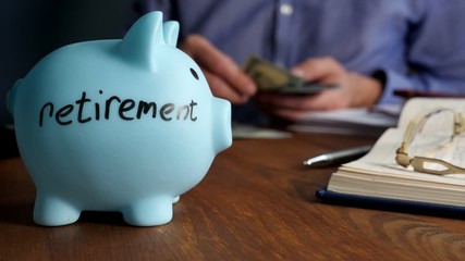 Piggy bank with sign retirement and man that counts money.