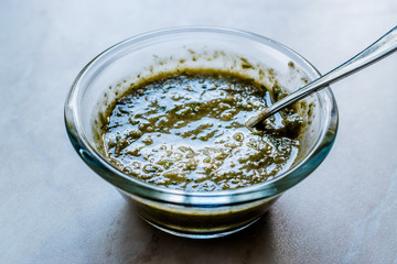 Homemade Green Herbal Salad Sauce with Plant Roots in Glass Bowl with Spoon.