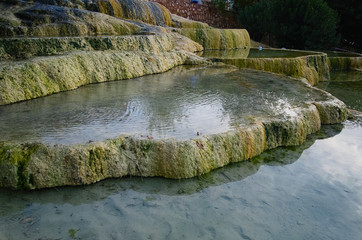 Red travertine terraces in Karahayit. Clear thermal water baths. Limestone formation with hot water. Pamukkale / Denizli, Turkey.