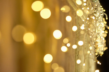 Beautiful bright festive fairy lights are hanging on a house wall and illuminating the dark night...
