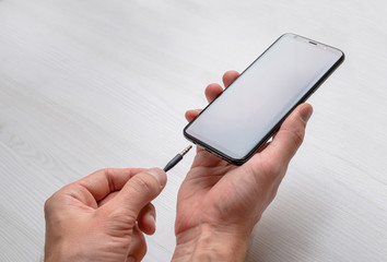 Connecting audio jack on a mobile phone. 3.5 mm audio jack and mobile phone in hands.
