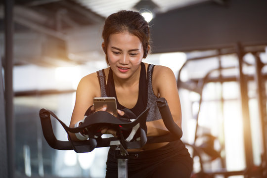 Active girl using smartphone in fitness gym.