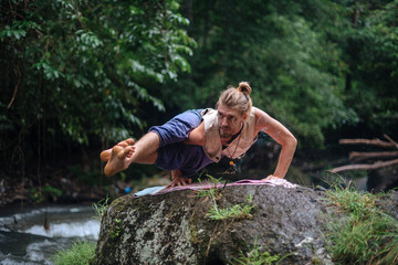 Naklejka na ściany i meble Yoga practice and meditation in nature. Man practicing near river