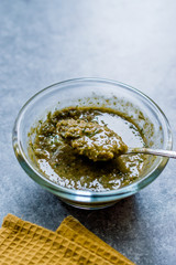 Homemade Green Herbal Salad Sauce with Plant Roots in Glass Bowl with Spoon.