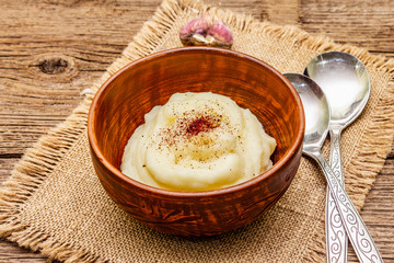 Homemade Thanksgiving garlic mashed potatoes with salt and pepper. Sackcloth napkin, spoons, old wooden boards background