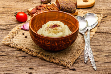 Homemade Thanksgiving garlic mashed potatoes with fresh tomatoes and pastrami. Sackcloth napkin, spoons, old wooden boards background