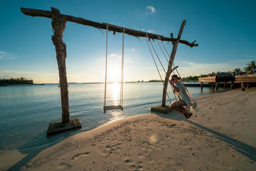 Fototapeta premium Woman uses a beach swing in the ocean at a luxury resort in the Maldives