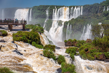 View to spectacular Iguazu Falls with visitor platform and blue sky